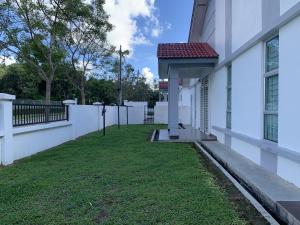 a side view of a white building with a yard at SRI KENANGA HOMESTAY in Bandar Penawar