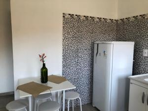 a kitchen with a white refrigerator and a table with stools at Flat Boa Vista Beach in Paraty