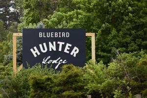 um sinal de alojamento de caçadores de pássaros azuis em frente às árvores em Hunter Lodge, a Bluebird by Lark em Hunter