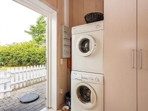a laundry room with a washer and dryer next to a door at Holiday Home Duevænget IV in Hemmet