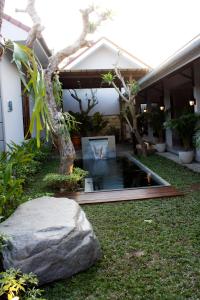 a garden with a pond in front of a house at Grand Marto Hotel in Yogyakarta