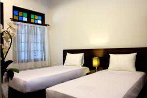 two beds in a room with a window at Grand Marto Hotel in Yogyakarta