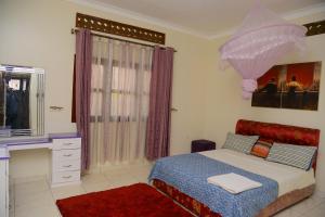 a bedroom with a bed and a desk and umbrella at MODERN LUXURIOUS 2BEDS HOUSE IN KAMPALA CITY CTR in Kampala