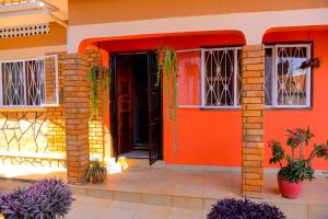 MODERN LUXURIOUS 2BEDS HOUSE IN KAMPALA CITY CTR في كامبالا: منزل برتقالي مع باب مفتوح