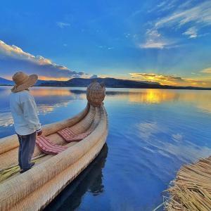 Un uomo in piedi sul fianco di una barca in acqua di Caminos Del Titicaca Lodge a Puno