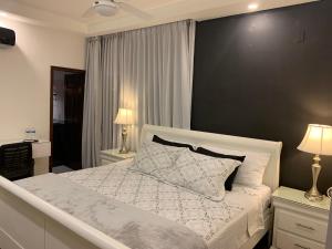 1 dormitorio con cama blanca y pared negra en MiCasa Stays, en Puerto Cortés