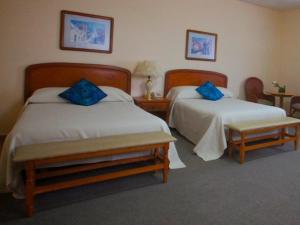 a hotel room with two beds with blue pillows at Villa Caltengo in Tulancingo