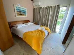 a bedroom with a bed with a yellow blanket on it at Fazenda Terra Bonita - Passeios a Cavalo e Trilhas in Serra de São Bento