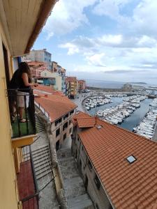 une femme debout sur un balcon donnant sur un port de plaisance dans l'établissement Precioso loft en Bermeo con vistas al mar, à Bermeo