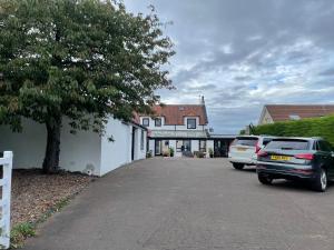 two cars parked in a parking lot next to a house at Golfers dream Guest suite with onsite golf studio available for booking by guests in Strathkinness