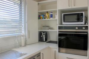 a kitchen with white cabinets and a microwave and a stove at City Centre Escape in Napier