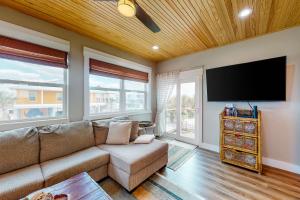 a living room with a couch and a flat screen tv at Cornerstone Beachside Cottage in Mexico Beach