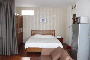 Dormitorio pequeño con cama y nevera en Davidduc's Apartment Nam Ngu en Hanói