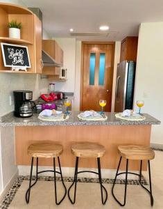 a kitchen with two bar stools and two glasses of wine at Vista al Lago con balcón en Mayan Lakes in Acapulco