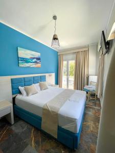 ein blaues Schlafzimmer mit einem Bett und einer blauen Wand in der Unterkunft Aphrodite Beach Hotel in Vatera