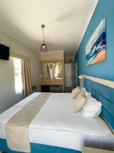 a bedroom with a large white bed with blue walls at Aphrodite Beach Hotel in Vatera