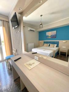 a bedroom with two beds and a desk with a tv at Aphrodite Beach Hotel in Vatera