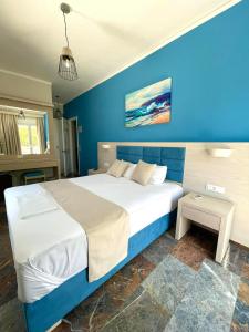 ein Schlafzimmer mit einem großen Bett mit blauer Wand in der Unterkunft Aphrodite Beach Hotel in Vatera