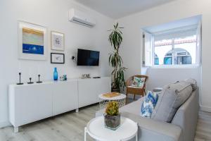 a white living room with a couch and a tv at Guadiana River Apartment in Vila Real de Santo António