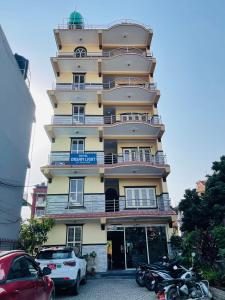 een hoog geel gebouw met auto's voor geparkeerd bij Hotel Dream Light in Pokhara