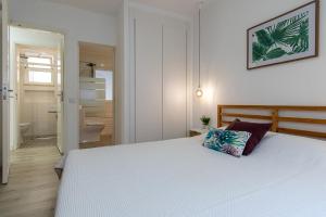 a bedroom with a large white bed and a bathroom at Guadiana River Apartment in Vila Real de Santo António