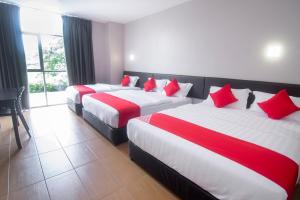 duas camas num quarto de hotel com almofadas vermelhas em Super OYO 897 iBC36 Business Stay em Kuching