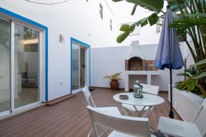 een terras met een tafel, stoelen en een parasol bij Guadiana River Apartment in Vila Real de Santo António