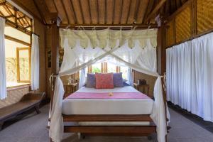 a bedroom with a canopy bed with white curtains at Bali Firefly BnB in Ubud