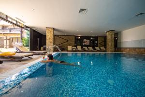 uma mulher deitada à beira de uma piscina em Hotel Bansko SPA & Holidays - Free Parking em Bansko