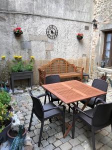 a wooden table and chairs with a bench in front of a building at Salardine Apartments - Cosy Suite in Châlus