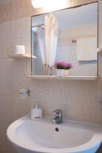 Studios Margarita في أرتيموناس: حمام مع حوض أبيض ومرآة