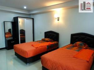 a bedroom with two beds with orange sheets and a mirror at Grand Airport Resort in Lat Krabang