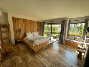 a bedroom with a bed and a large window at Mantadia Lodge Andasibe in Andasibe