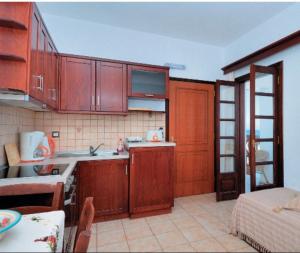 a kitchen with wooden cabinets and a table in a room at Achinos Apartments and Maisonettes in Kokkari