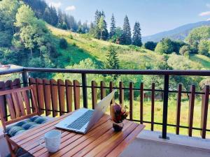 um computador portátil sentado numa mesa de madeira numa varanda em Ani's Guest House em Chepelare