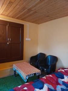 a room with two chairs and a bed and a table at NotOnMap- Amaira Homestay in Khajjiar  +2 photos