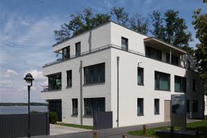 a white building with windows and a body of water at Gerono - Haus am See in Wusterwitz