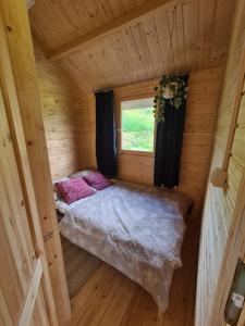 a small room with a bed in a wooden cabin at Jesionowe Domki in Zełwągi +35 photos