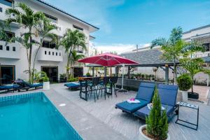 a patio with a pool and chairs and an umbrella at DEL MAX Resort Pattaya in Pattaya South