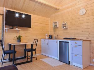 a kitchen with a table and a tv on the wall at Jesionowe Domki in Zełwągi