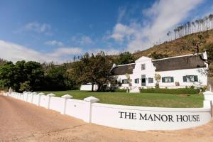a white house with a sign that reads the manor house at Rickety Bridge Manor House in Franschhoek