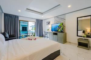 a bedroom with a large white bed and a television at DEL MAX Resort Pattaya in Pattaya South