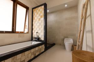 ein Badezimmer mit Badewanne, Toilette und Waschbecken in der Unterkunft Villa Casa Orana in Seminyak