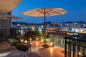 a balcony with an umbrella and chairs and lights at D & E APARTMENTS in Skiathos Town