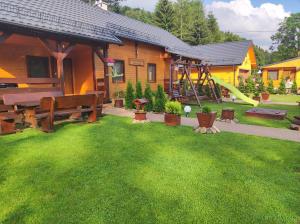 a backyard with a playground with a bench and a slide at Drewniany Domek Daria i Tomek 2 domki na 8 osób in Stronie Śląskie