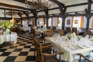 a restaurant with white tables and chairs and a checkered floor at Hotel Niedersächsischer Hof in Bad Bentheim