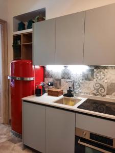 a kitchen with white cabinets and a red refrigerator at Borromini Home in Turin