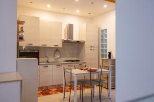 cocina con armarios blancos, mesa y sillas en Andrea's House, en Locri