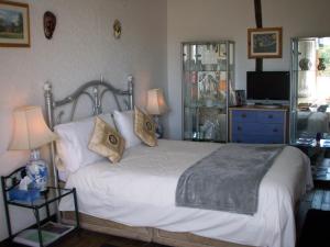 Un dormitorio con una cama blanca con almohadas y un televisor. en La Châtaigne Dorée, en Saint-Pierre-de-Fursac