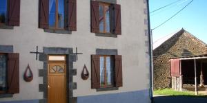 un edificio con una puerta y ventanas. en La Châtaigne Dorée, en Saint-Pierre-de-Fursac